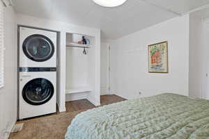 Carpeted bedroom with a closet and stacked washer and clothes dryer