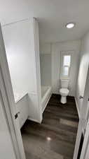 Bathroom with vanity, toilet, wood-type flooring, and a tub