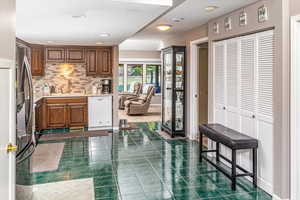 Kitchen featuring decorative backsplash, a kitchen bar, sink, dishwasher, and stainless steel refrigerator