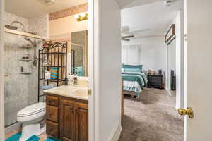 Bathroom featuring ceiling fan, vanity, a shower with shower door, and a textured ceiling