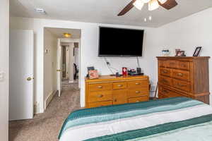 Bedroom featuring ceiling fan, light colored carpet, and a textured ceiling