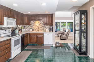 Kitchen with decorative backsplash, sink, dark tile patterned floors, and white appliances