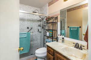 Bathroom featuring tile patterned floors, vanity, toilet, and a shower with shower door