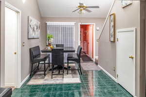 Tiled dining area with ceiling fan and lofted ceiling