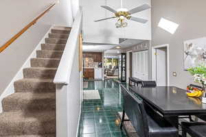 Interior space with a towering ceiling, a skylight, tile patterned floors, and ceiling fan