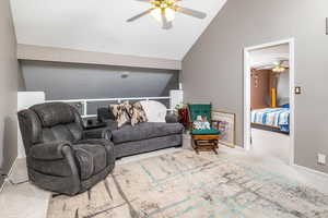 Carpeted living room with ceiling fan and high vaulted ceiling