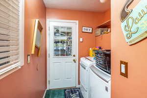 Washroom featuring independent washer and dryer, a textured ceiling, and dark tile patterned flooring