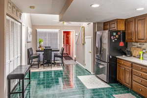 Kitchen featuring decorative backsplash, stainless steel fridge, and dark tile patterned flooring