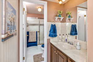 Full bathroom featuring vanity, shower / bath combination with glass door, tile patterned floors, toilet, and a textured ceiling