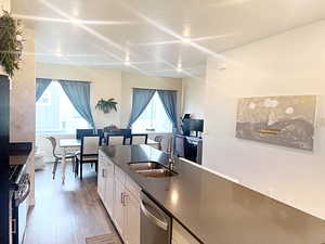 Kitchen featuring plenty of natural light, wood-type flooring, white cabinetry, and stainless steel appliances