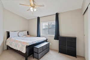 Bedroom with ceiling fan, light carpet, and a textured ceiling