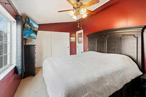 Carpeted bedroom featuring ceiling fan and vaulted ceiling