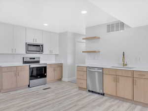 Kitchen featuring light brown cabinetry, sink, light hardwood / wood-style flooring, and appliances with stainless steel finishes