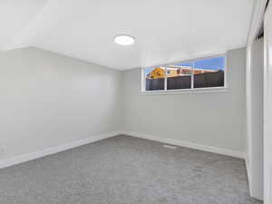 Carpeted empty room with vaulted ceiling