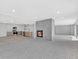 Unfurnished living room featuring a tile fireplace, light carpet, and sink