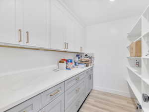 Interior space featuring light hardwood / wood-style floors, light stone counters, and white cabinetry