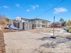 Rear view of house with basketball hoop and a balcony