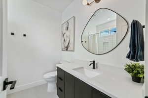 Bathroom featuring a shower with curtain, vanity, and toilet