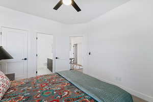 Bedroom with ceiling fan, light colored carpet, and ensuite bathroom