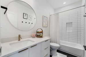 Full bathroom with tile patterned floors, shower / tub combo with curtain, vanity, and toilet