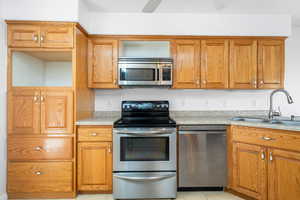 Kitchen featuring ceiling fan, sink, light tile patterned flooring, and stainless steel appliances