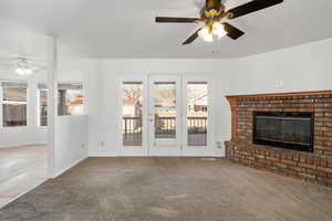 Unfurnished living room with carpet, ceiling fan, and a brick fireplace