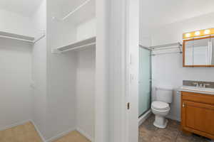 Bathroom featuring vanity, a shower with shower door, and toilet