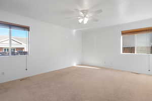 Carpeted empty room featuring ceiling fan and ornamental molding