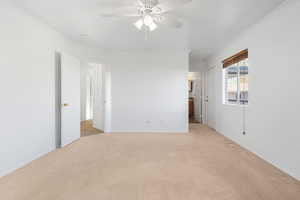 Empty room featuring crown molding, ceiling fan, and light colored carpet