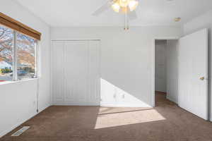 Unfurnished bedroom featuring ceiling fan, a closet, and dark colored carpet