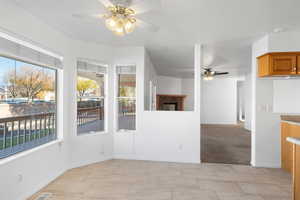 Interior space with ceiling fan, light colored carpet, and a brick fireplace