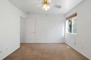 Carpeted empty room featuring ceiling fan