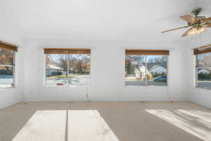 Carpeted empty room featuring ceiling fan and a healthy amount of sunlight