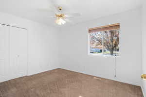 Unfurnished bedroom featuring ceiling fan, a closet, and carpet floors