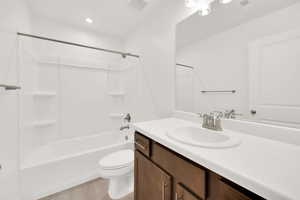 Full bathroom with hardwood / wood-style floors, vanity, toilet, and bathing tub / shower combination