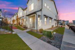 Property exterior at dusk with central air condition unit and a lawn