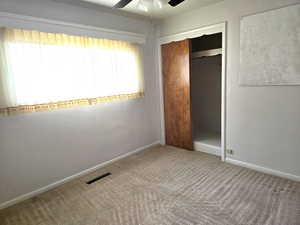 Unfurnished bedroom with ceiling fan, a closet, and carpet