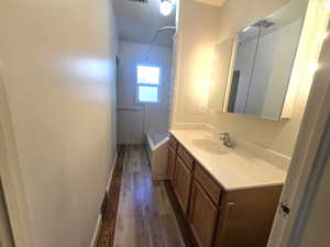 Bathroom with hardwood / wood-style flooring, vanity, and shower / tub combination