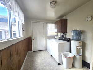 Clothes washing area featuring washer and dryer, wooden walls, and cabinets