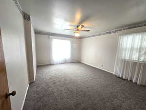 Empty room with dark colored carpet and ceiling fan