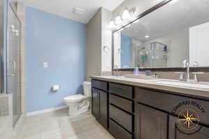 Primary Bathroom featuring tile patterned flooring, vanity, toilet, and an enclosed shower