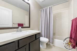 Full bathroom with tile patterned flooring, shower / bath combo, vanity, and toilet