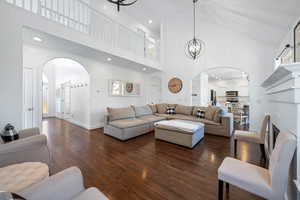 Living room with high vaulted ceiling, dark hardwood / wood-style floors, and a notable chandelier