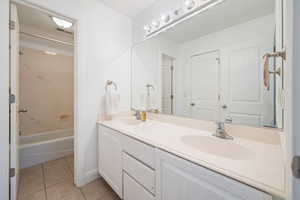 Bathroom featuring tile patterned flooring, vanity, and tub / shower combination