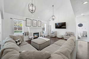 Living room with dark hardwood / wood-style flooring, high vaulted ceiling, a textured ceiling, and a notable chandelier