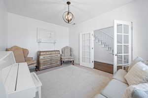 Carpeted living room featuring a chandelier and french doors