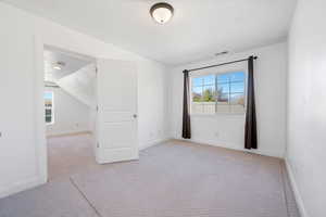 Carpeted empty room featuring lofted ceiling