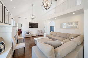 Living room with dark hardwood / wood-style flooring, high vaulted ceiling, and a notable chandelier