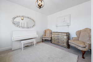 Sitting room featuring light colored carpet and an inviting chandelier