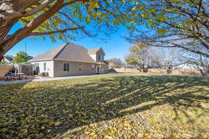 Rear view of house with a lawn, a shed, a patio, and central AC